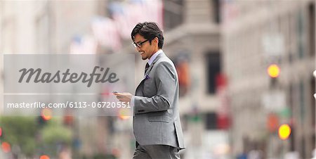 Businessman using cell phone on city street