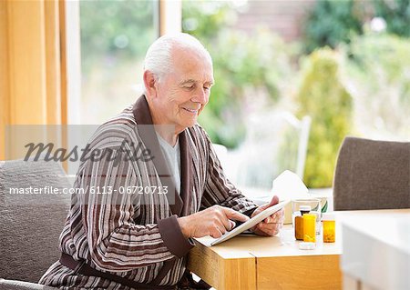 Older man using tablet computer at table