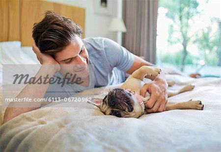 Man petting dog on bed