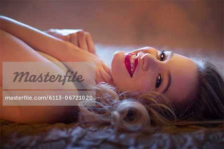 Smiling nude woman laying on bed
