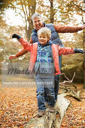 Man and grandson playing on log in park