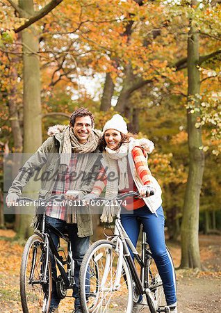 Couple riding bicycles together in park
