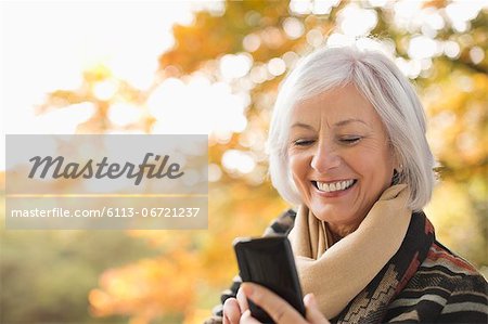 Older woman using cell phone in park