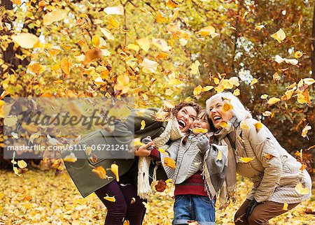 Three generations of women playing in autumn leaves