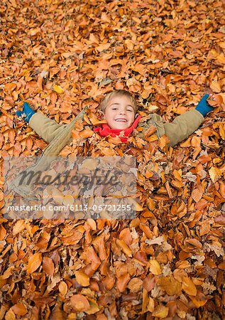 Boy laying in autumn leaves