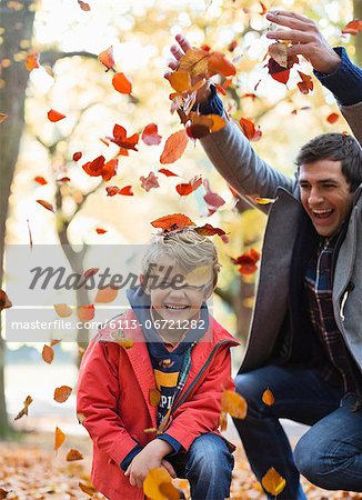 Father and son playing in autumn leaves Father and son playing in autumn leaves