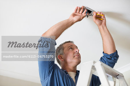 Electrician working on ceiling lights