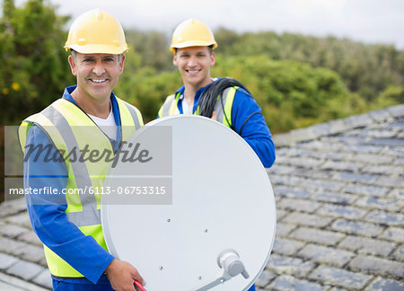 Workers installing satellite dish on roof