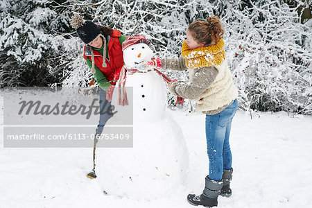 Mother and daughter making snowman