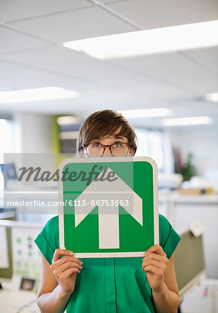 Businesswoman holding arrow sign in office