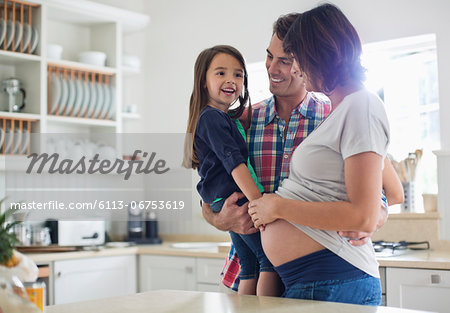 Girl touching pregnant mother's belly