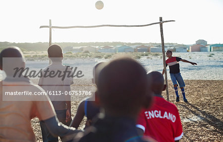 Boys playing soccer together in dirt field