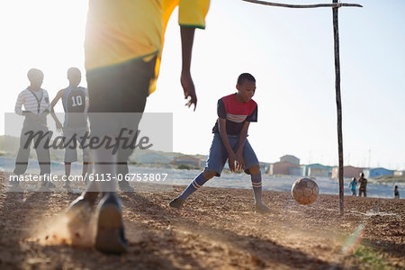 Boys playing soccer together in dirt field