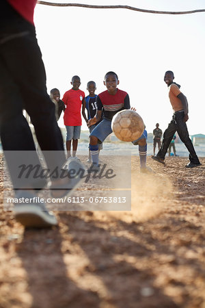 Boys playing soccer together in dirt field