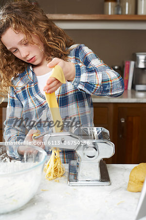 Girl rolling pasta dough in kitchen