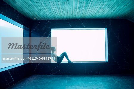 Woman sitting on ledge at window in pool room