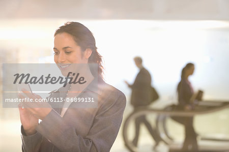 Smiling businesswoman text messaging with cell phone