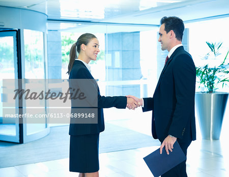 Smiling businessman and businesswoman handshaking in lobby