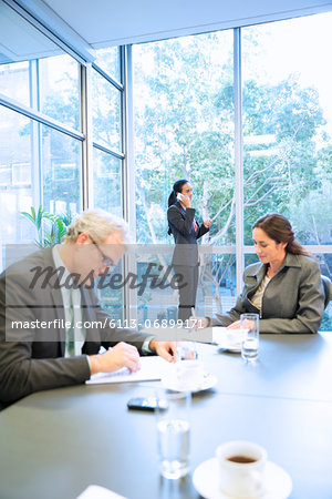 Businesswoman talking on cell phone at window in conference room