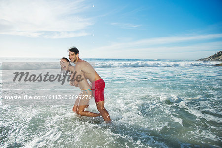 Enthusiastic couple hugging and splashing in ocean
