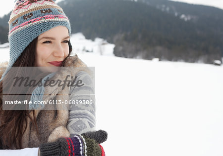 Happy woman wearing knit hat and gloves in snowy field