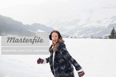 Portrait of enthusiastic woman running in snowy field