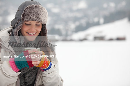 Smiling woman drinking coffee in snow