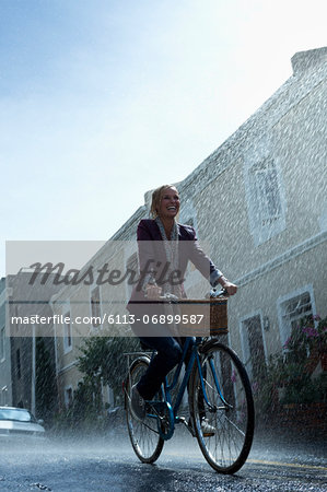 Happy woman riding bicycle in rainy street