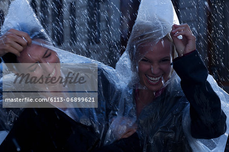 Laughing businesswomen wearing ponchos in rain