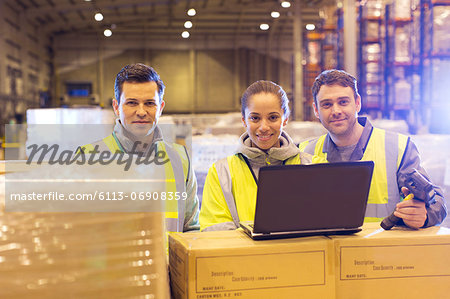 Workers using laptop in warehouse