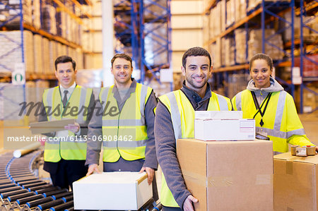 Workers smiling by conveyor belt in warehouse