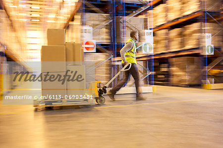 Blurred view of worker carting boxes in warehouse