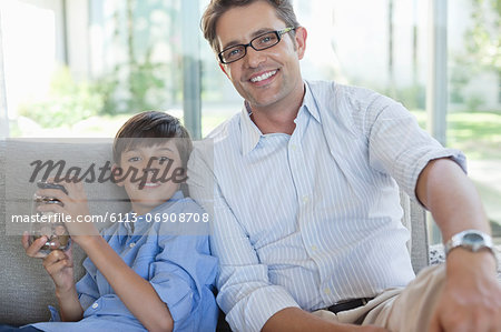 Father and son with change jar on sofa