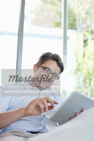Man using tablet computer on sofa Man using tablet computer on sofa