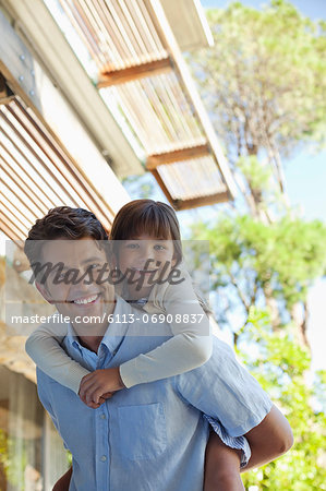 Father carrying daughter piggy back outdoors