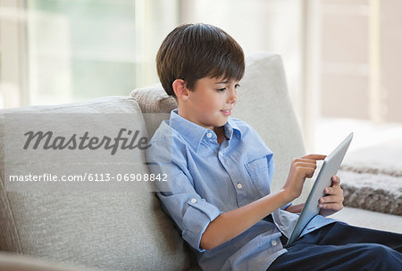 Boy using tablet computer on sofa