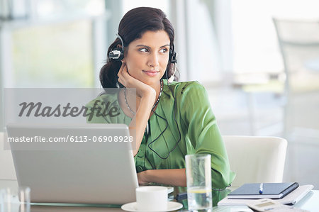 Businesswoman wearing headphones at desk