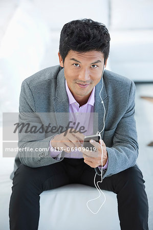 Businessman listening to headphones on sofa