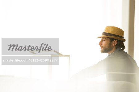 Man in straw hat looking out window