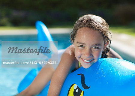 Girl riding inflatable toy in swimming pool