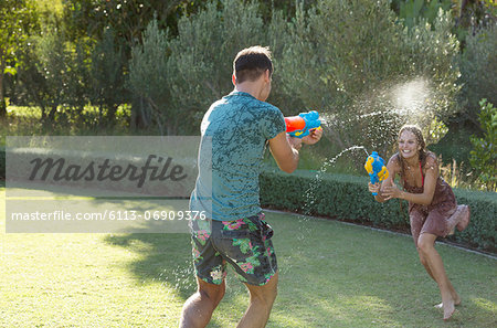 Couple playing with water guns in backyard