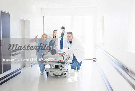 Doctors and nurses rushing patient on stretcher down hospital corridor Doctors and nurses rushing patient on stretcher down hospital corridor