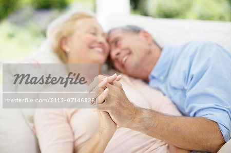 Senior couple holding hands on sofa