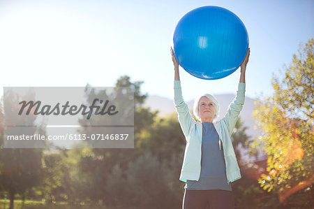 Senior woman holding fitness ball in park