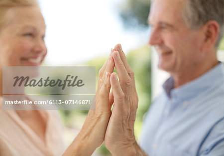 Senior couple touching hands on patio