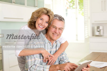 Portrait of smiling senior couple with digital tablet in kitchen