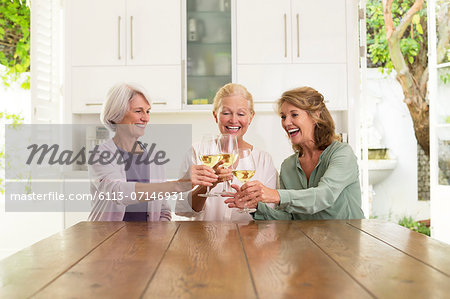 Senior women toasting wine glasses in kitchen