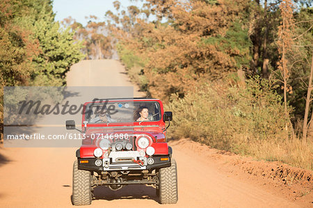 Couple driving sport utility vehicle on dirt road