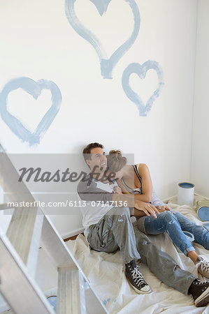 Couple painting blue hearts on wall