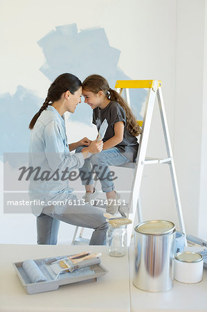 Mother and daughter painting wall blue Mother and daughter painting wall blue